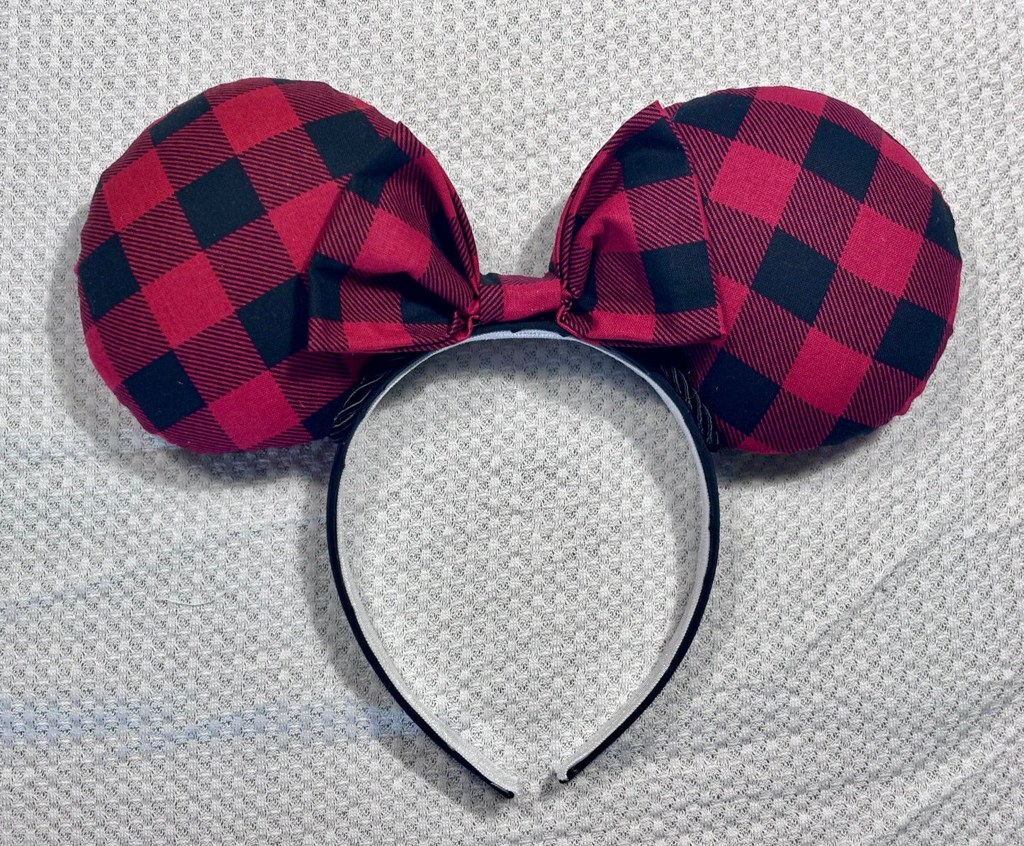 Handmade and ready to ship Buffalo Plaid mouse ears on both the front and back. On a black headband that is universal sized. The set has a matching buffalo plaid bow. Item is shown on a white background.