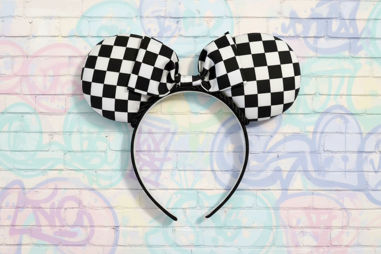 Checkered mouse ears headband with a matching bow on a black headband. Shown on a pastel wooden background
