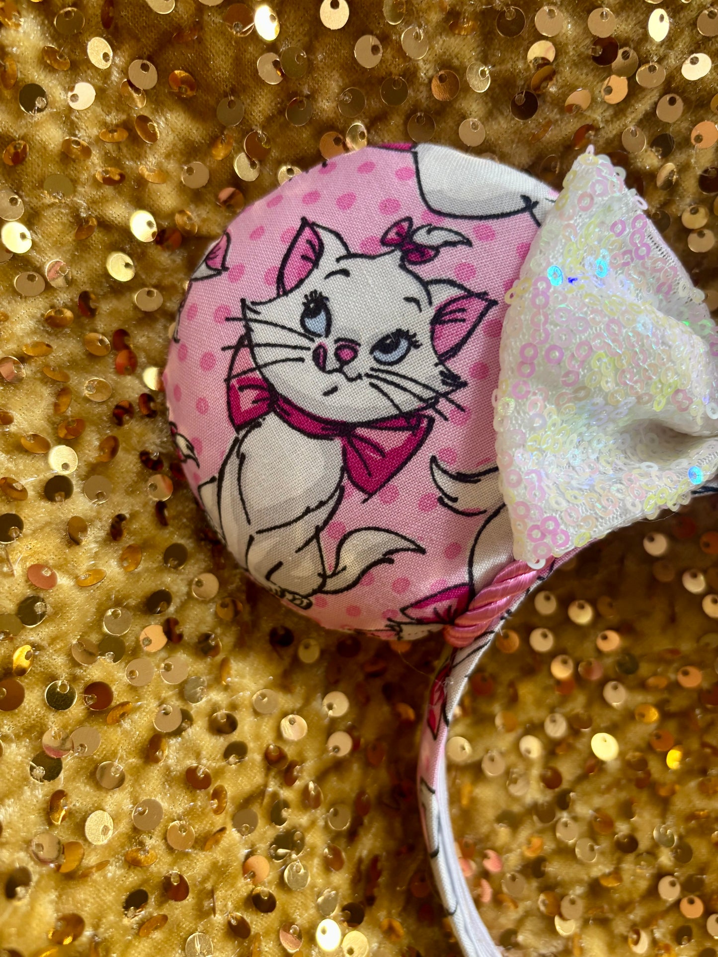 Pink mouse ear headband with white bow shown on a gold glitter background