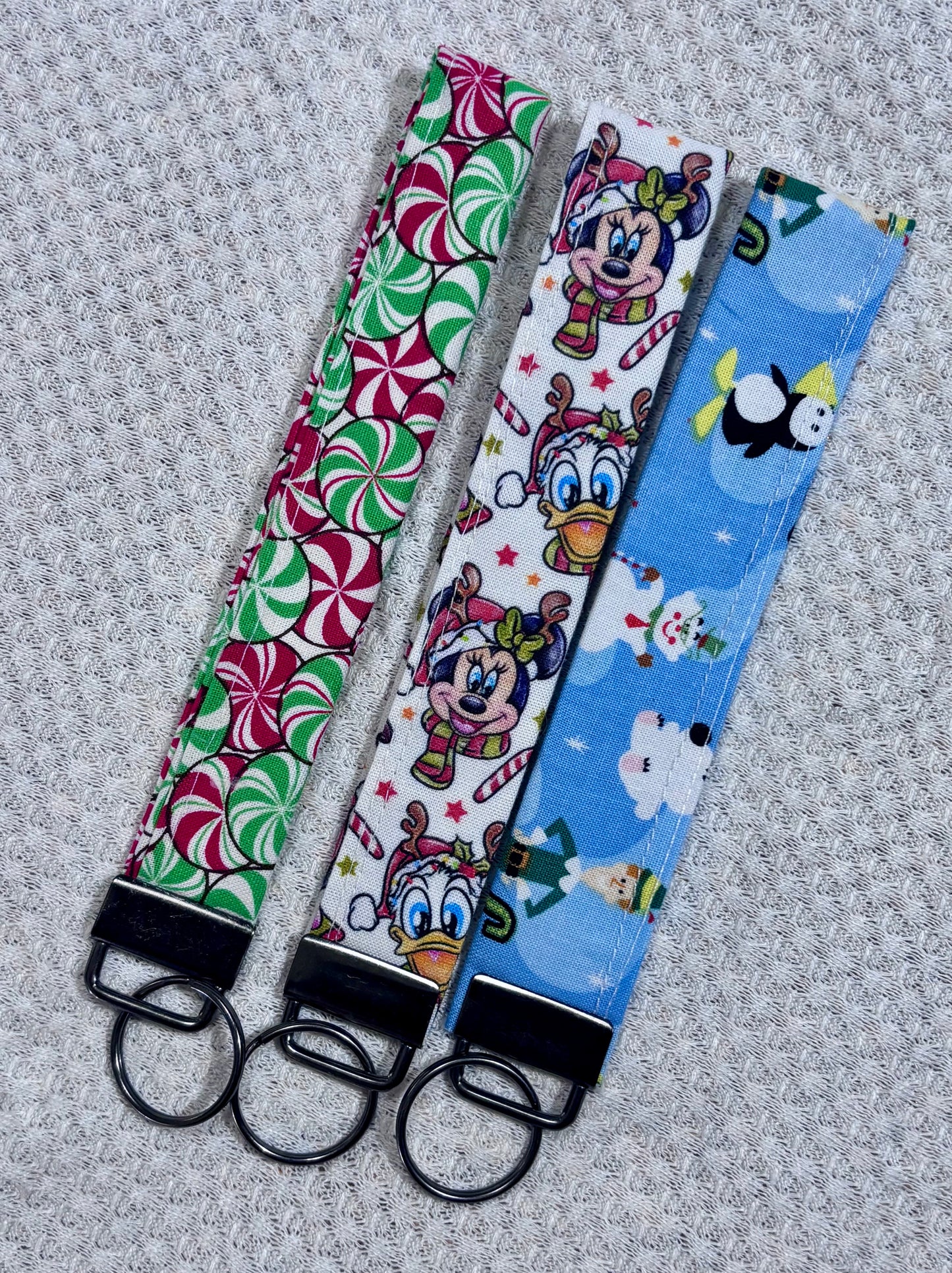 Three fabric keychains with different patterns on a textured gray background