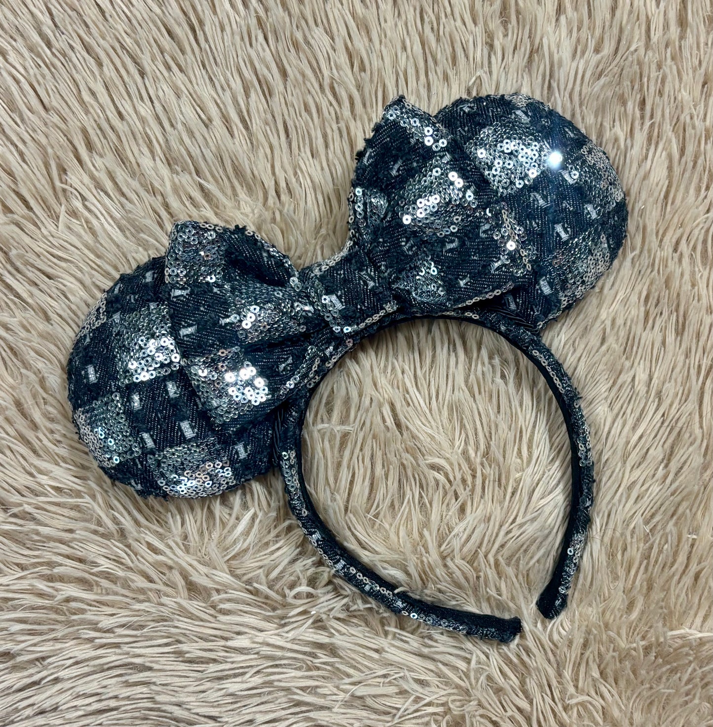 A black and silver checkered sequined headband with large bow ears.