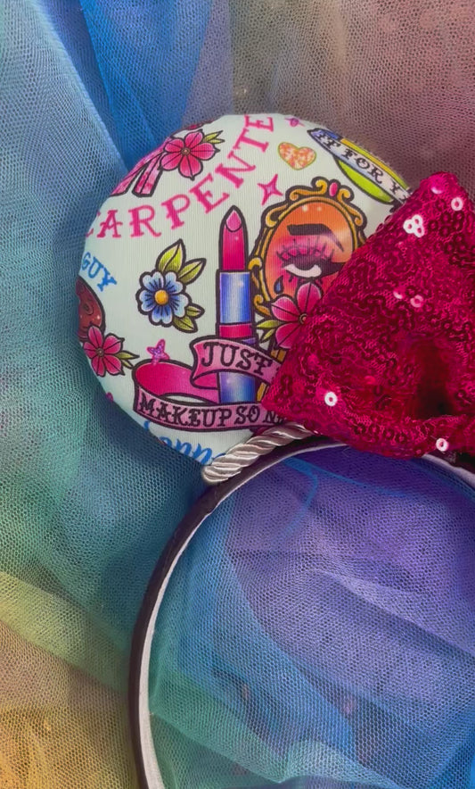 Cartoon SC-themed mouse ears on a black headband with a hot pink sequin bow. Shown on a colorful background.