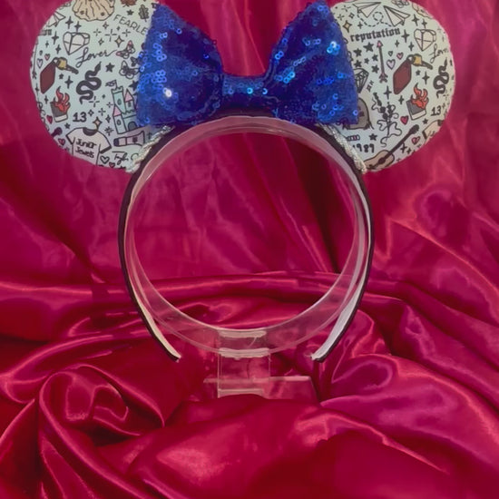 Handmade and ready to ship Tay Doodles mouse ears with drawings and titles of albums on fabric on a black universal headband, with silver trim and a blue sequin bow.