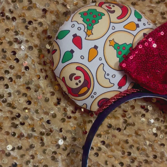 Christmas Sugar Cookie mouse ears with the fabric on both the front and back. The headband is black universal sized and fits most. The set has a red sequin bow. Item is shown on a gold sequin background.