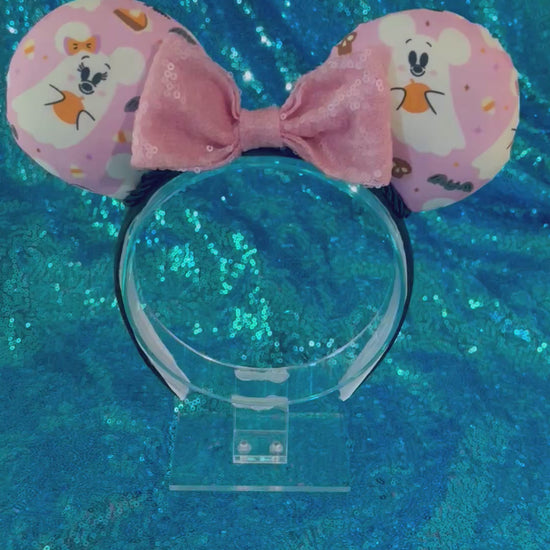 Handmade and ready to ship Halloween Pink Ghosts Mouse ears with the fabric with mouse shaped ghosts on pink fabric is on the ears, front and back and a light pink sequin bow. The headband is a universal sized headband and has black poly cotton fabric on it.