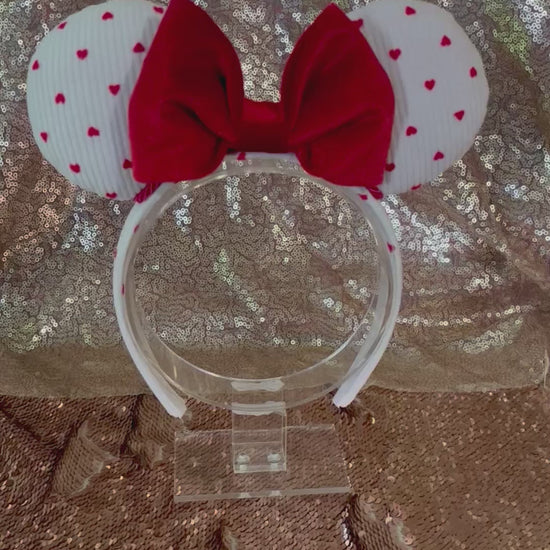 Handmade and ready to ship, Be Mine Custom Ears. Fabric is on ears front and back with red twisted trim along the inner ears and a big puffy plush red bow. The Headband is universal sized and has the same white fabric with hearts pattern on it.