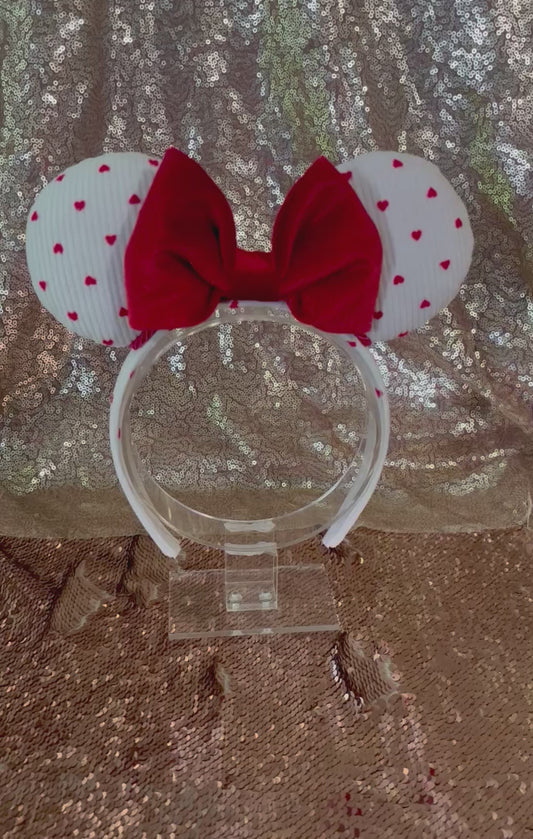 Handmade and ready to ship, Be Mine Custom Ears. Fabric is on ears front and back with red twisted trim along the inner ears and a big puffy plush red bow. The Headband is universal sized and has the same white fabric with hearts pattern on it.