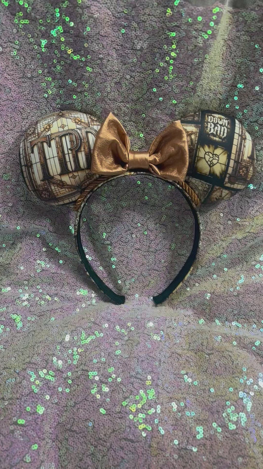 Mouse ear headband in TTPD design with a black sequin bow on a textured gray surface.