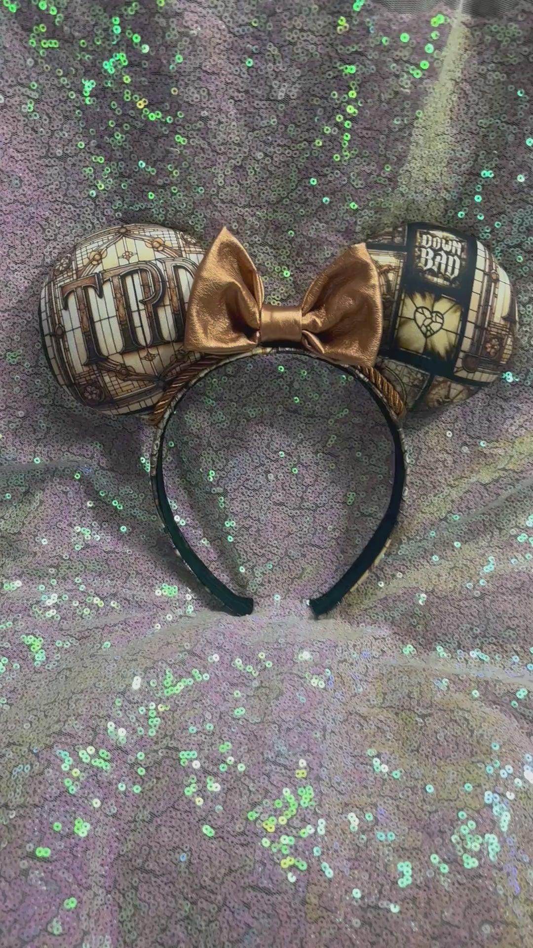 Mouse ear headband in TTPD design with a black sequin bow on a textured gray surface.