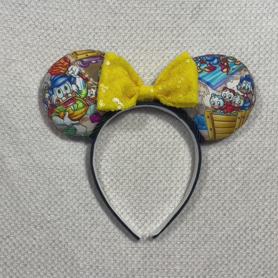 Handmade and ready to ship Colorful mouse ears with DuckTales Inspired fabric on the ears front and back with a Yellow Sequin bow on a universal sized black poly cotton fabric headband.