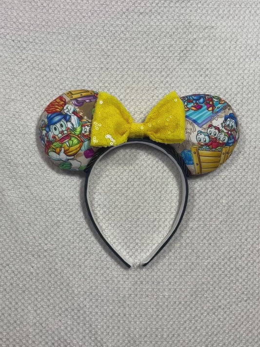 Handmade and ready to ship Colorful mouse ears with DuckTales Inspired fabric on the ears front and back with a Yellow Sequin bow on a universal sized black poly cotton fabric headband.