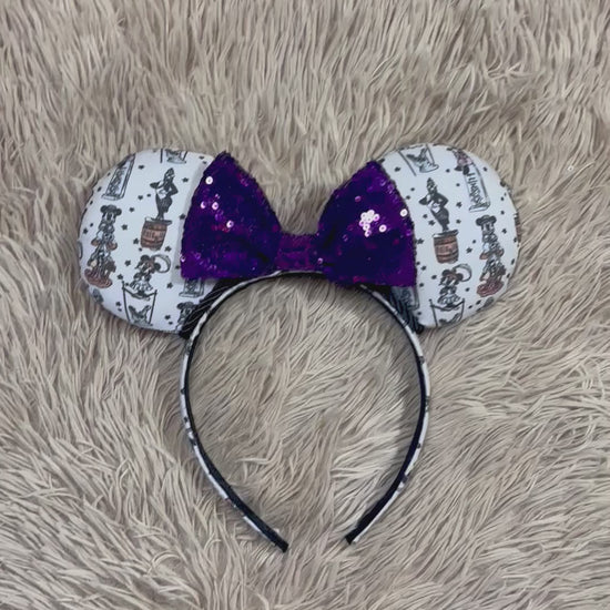 A set of ears with a fab 5 stretching room fabric on the ears front and back along with the headband as well. Black twisted trim along the inner ears with a purple sequin bow. 