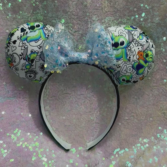 Handmade and ready to ship Mouse ears with Stitch cartoon character design on the fabric with silver twisted trim on a black universal sized headband and a blue sequin bow.