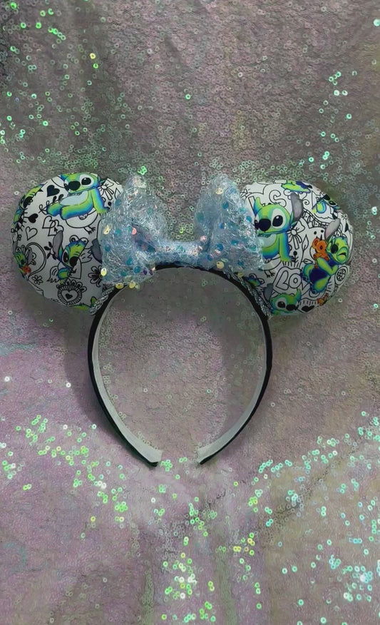 Handmade and ready to ship Mouse ears with Stitch cartoon character design on the fabric with silver twisted trim on a black universal sized headband and a blue sequin bow.