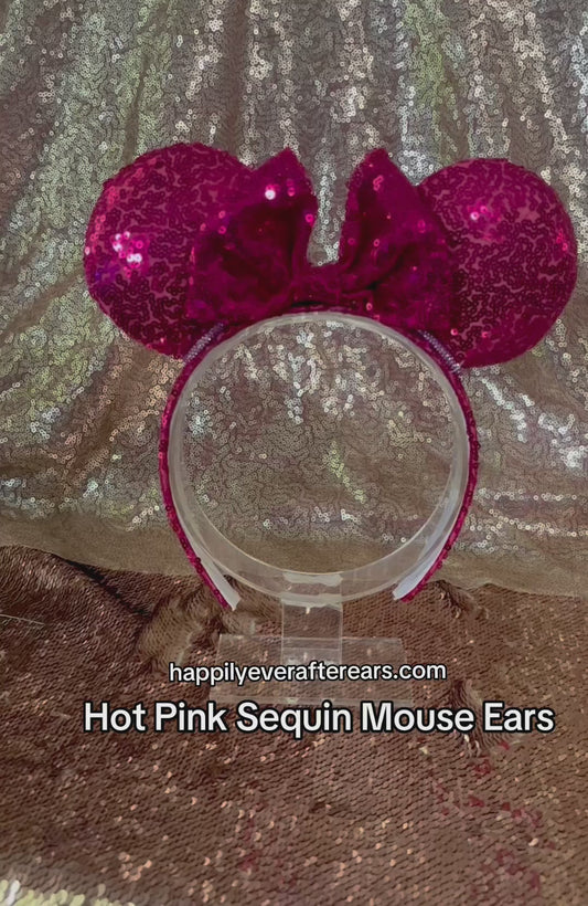 A pair of pink sequined ears on a universal sized headband with white elastic lining and a rhinestone trim along the inner ears. 