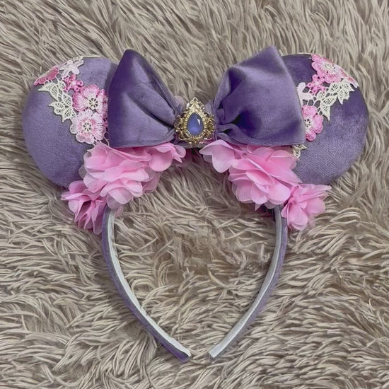 Purple and pink fabric mouse ears headband with a large velvet bow, floral lace appliques, and a purple gem accent.