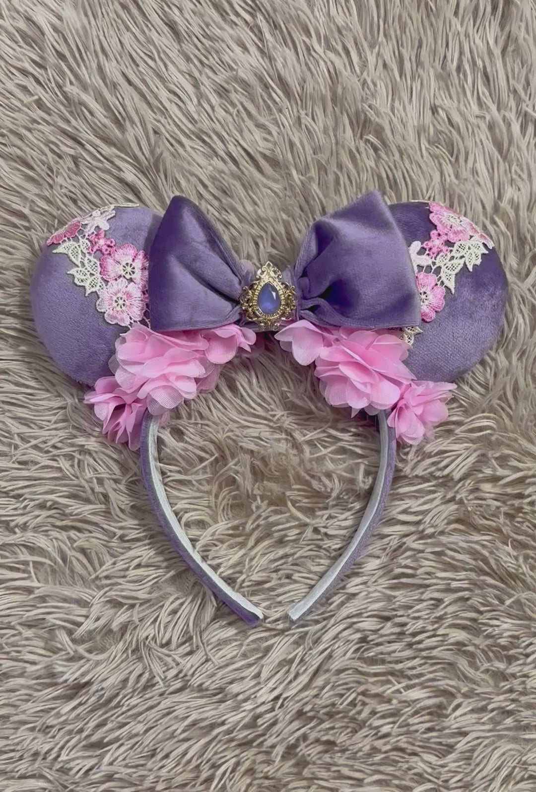 Purple and pink fabric mouse ears headband with a large velvet bow, floral lace appliques, and a purple gem accent.
