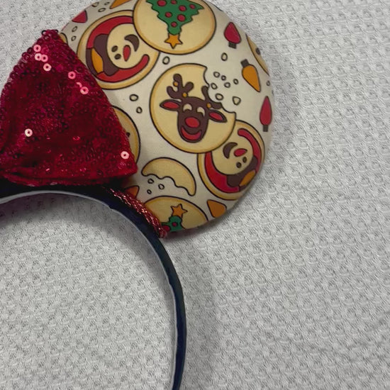 Christmas Sugar Cookie mouse ears with the fabric on both the front and back. The headband is black universal sized and fits most. The set has a red sequin bow. Item is shown on a white background.