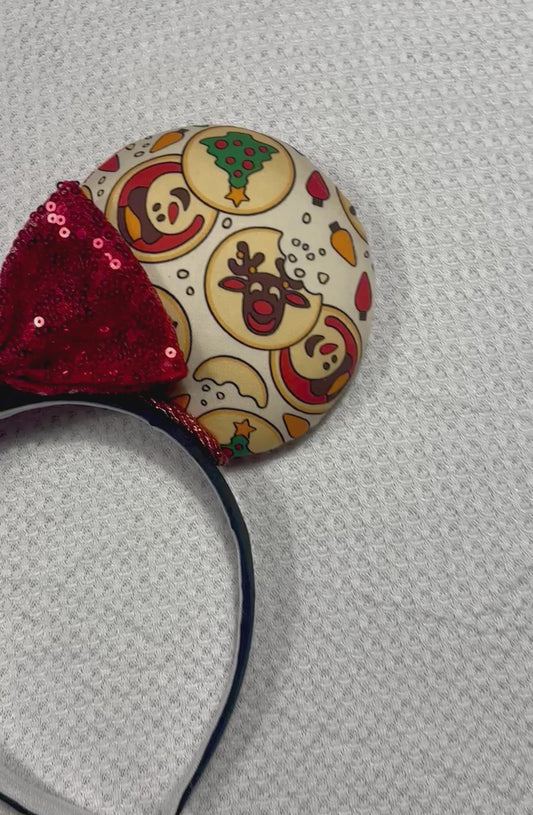 Christmas Sugar Cookie mouse ears with the fabric on both the front and back. The headband is black universal sized and fits most. The set has a red sequin bow. Item is shown on a white background.