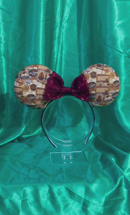 Tower of Terror inspired fabric on front, back and the headband as well. These are handmade and ready to ship mouse ears with a maroon sequin bow. Shown on a green satin background.