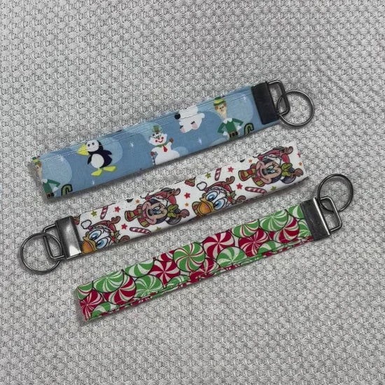 Three colorful keychains with different designs on a textured gray surface. Handmade and ready to ship.