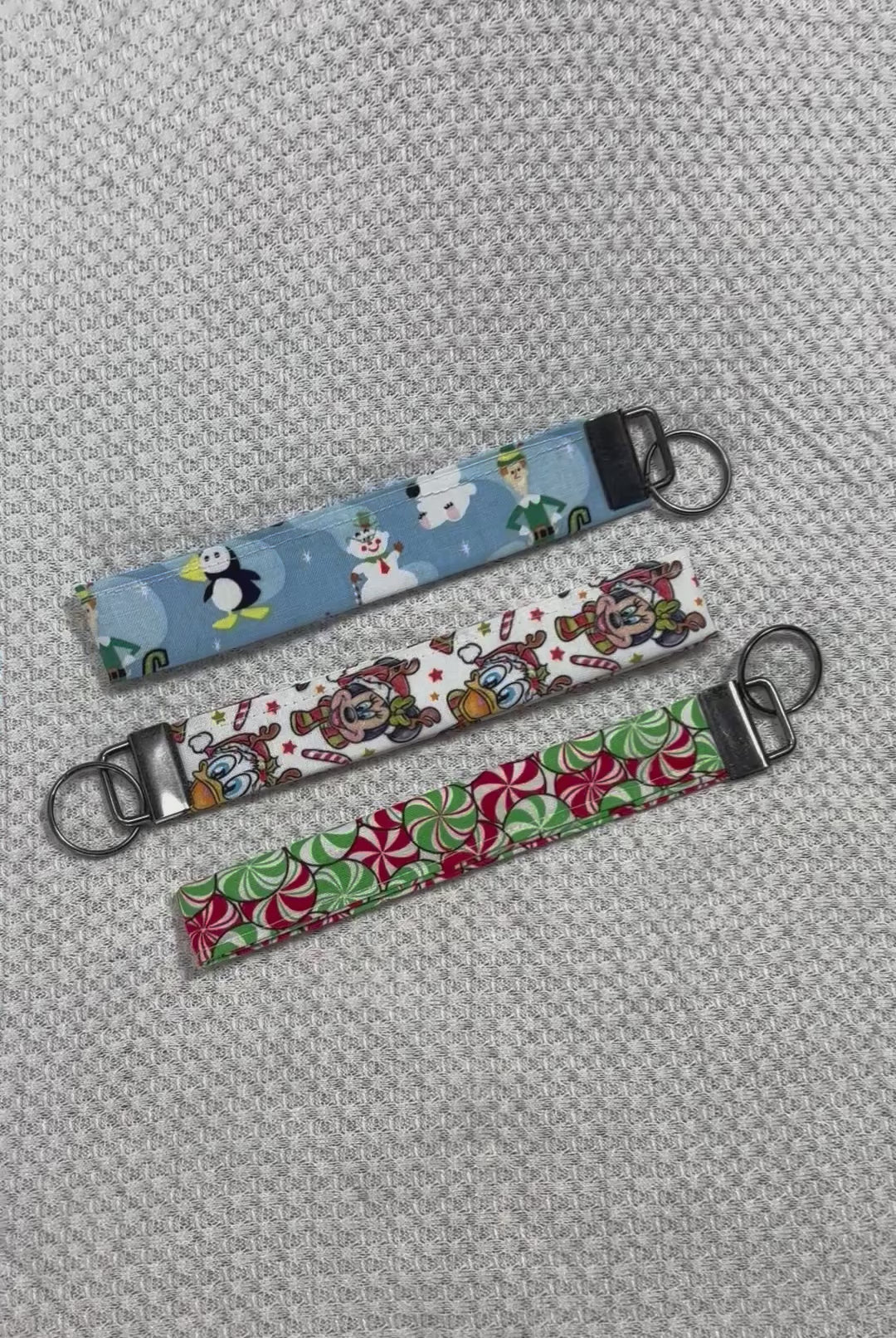 Three colorful keychains with different designs on a textured gray surface. Handmade and ready to ship.