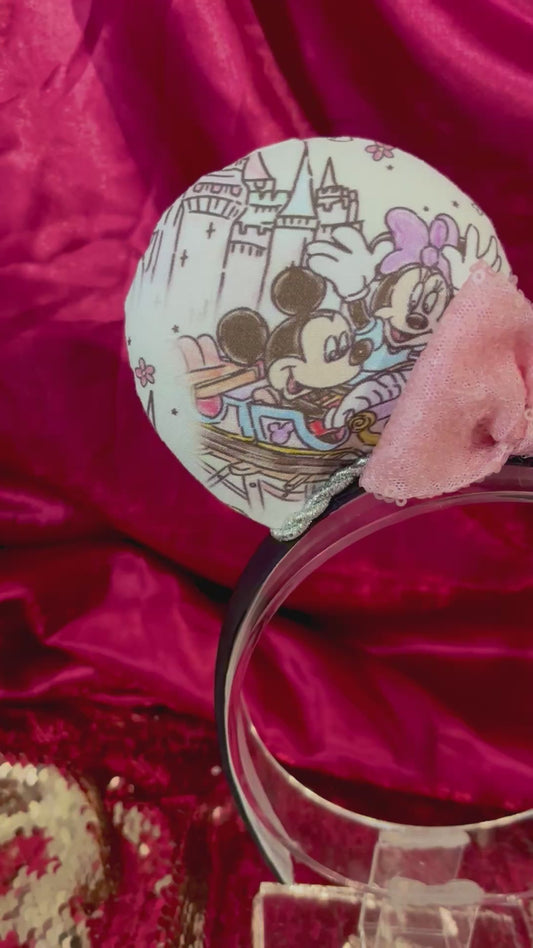 Mouse ears with a colorful design and light pink sequin bow on a satin background