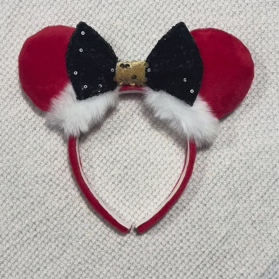 Minnie Mouse ears headband with red plush ears and black bow with gold middle and fluffy white trim on a white background