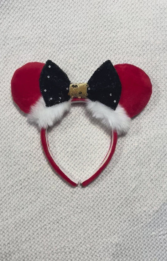 Minnie Mouse ears headband with red plush ears and black bow with gold middle and fluffy white trim on a white background
