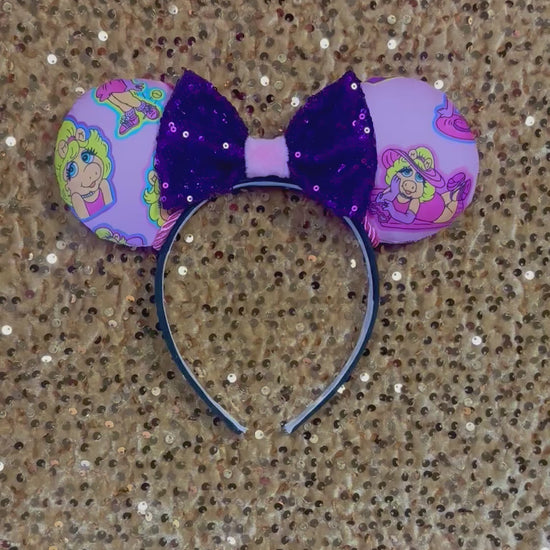 Handmade and ready to ship Piggy mouse ears. Miss Piggy fabric is on the front and the back. On a universal sized black poly fabric headband. With a purple sequin with pink soft middle on the bow. 