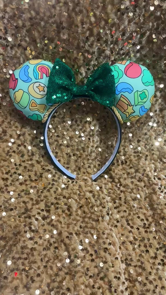 Handmade and ready to ship custom ears with lucky marshmallows on the fabric front and back with a green sequin bow and gold trim on a universal sized black poly cotton headband.