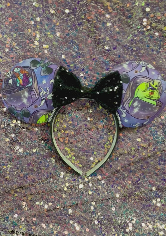NBC Mashup mouse ears. The fabric is on both the front and back. The headband is black and lined with white elastic. Shown with a black sequin bow. Item is shown on a glitter background. Fabric placement varies per set.