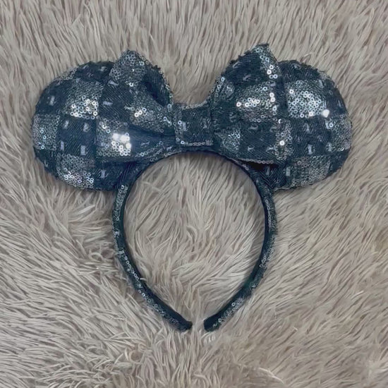 A black and silver checkered sequined headband with large bow ears.