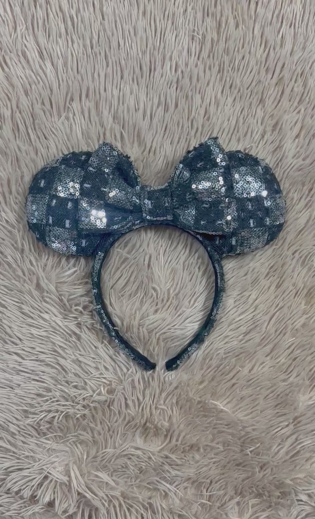 A black and silver checkered sequined headband with large bow ears.