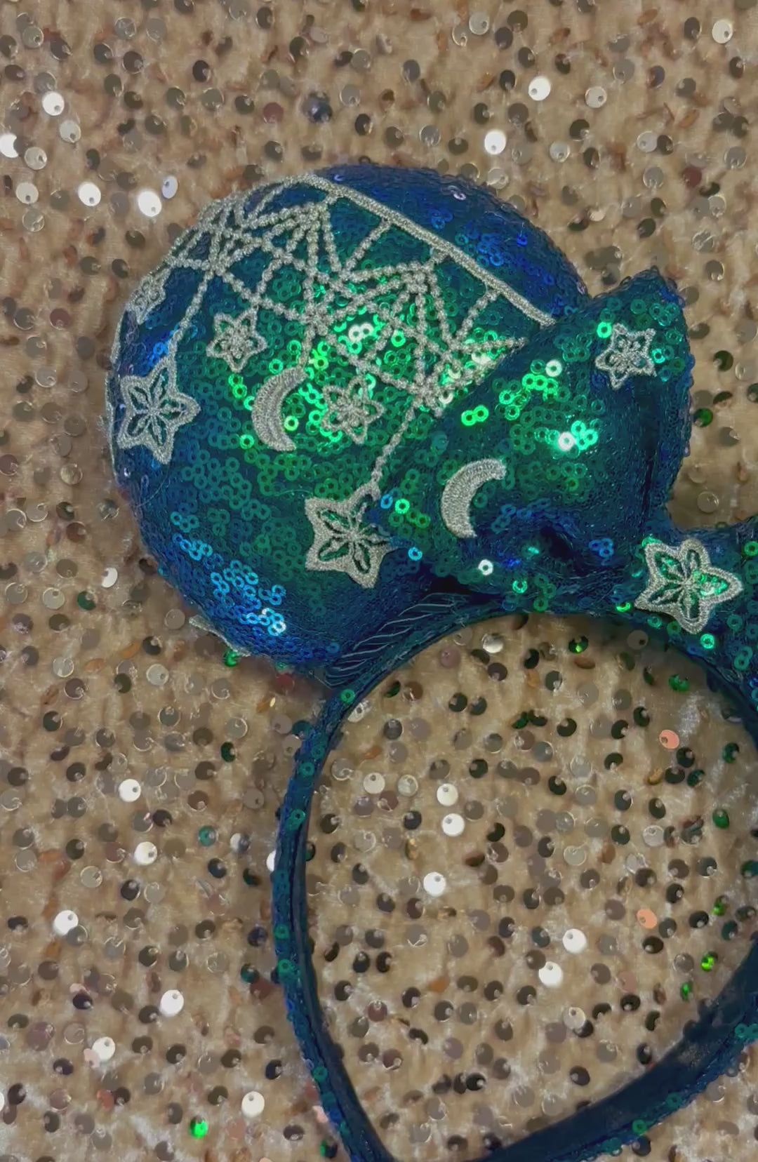 Mouse Ear headband that is a Handmade Iridescent blue and green sequins with gold sun, moon and stars attached to them. bow with star and moon patterns.