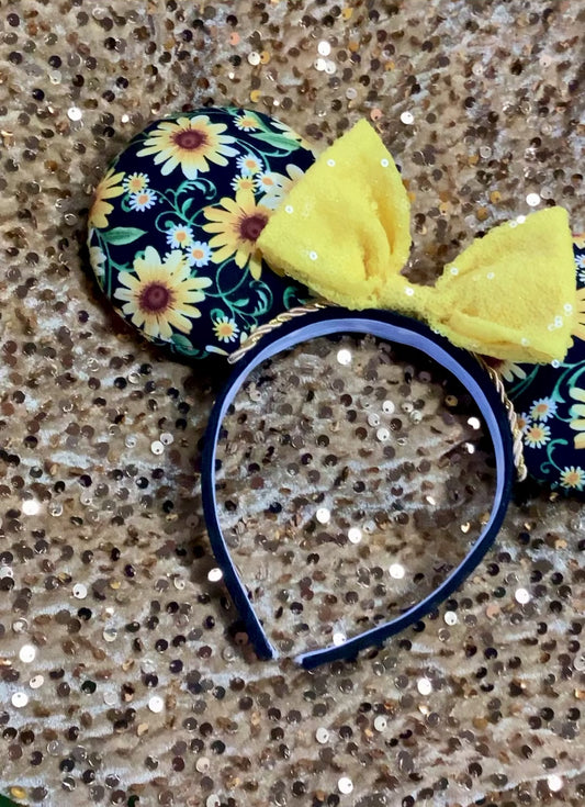 Yellow Floral Mouse Ears with a yellow sequin bow on a glittery background