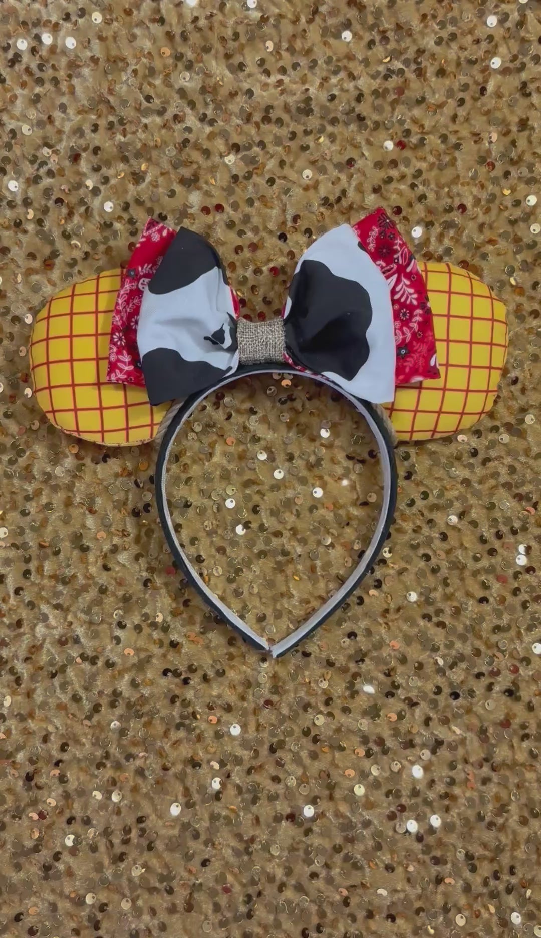 Handmade and ready to ship. Sheriff Woody Inspired mouse ears with the fabric on both the front and back that looks like his shirt. The fabric on the headband is black and is universal sized and fits most. The set has a bandana and cow print layered bow with brown trim along the inner ears to look like rope. Item is shown on a gold background.
