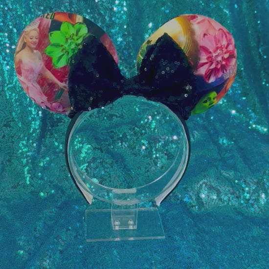 Mouse ears with floral design and black sequin bow on a blue glitter surface