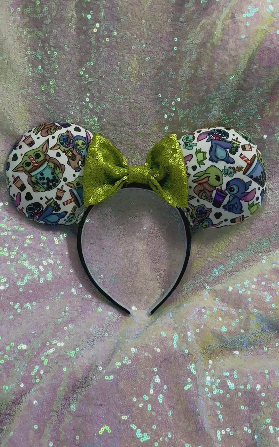 Handmade and ready to ship. Stitch and Baby Yoda are drinking coffee on the front and back with a lime green sequin bow. Shown on a white glitter background.