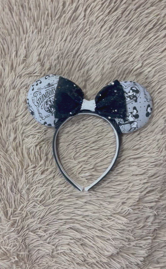 A pair of Mouse-themed ear headbands featuring a black and white patterned fabric with sequins, a black sequined bow with a white sequin middle, and a black with white elastic lining headband.